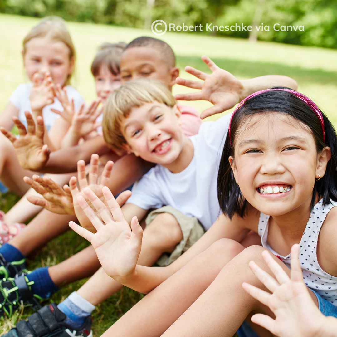 Group of smiling school age children sitting outside