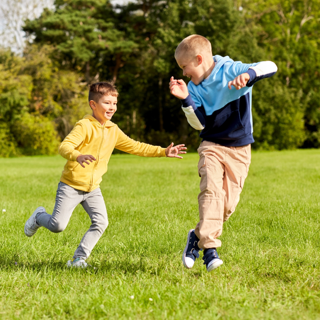 Two school age kids playing outside on the grass