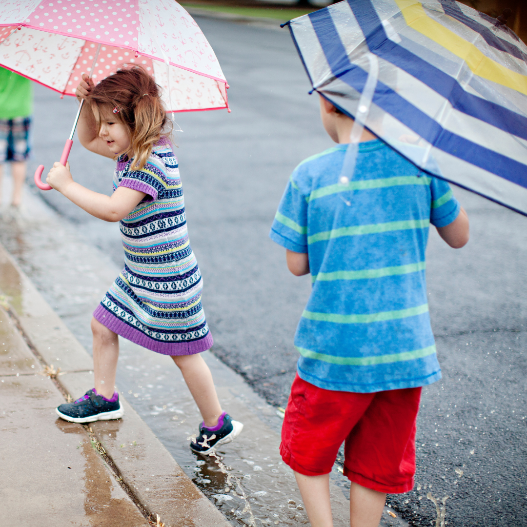 Two kids outside with umbrellas