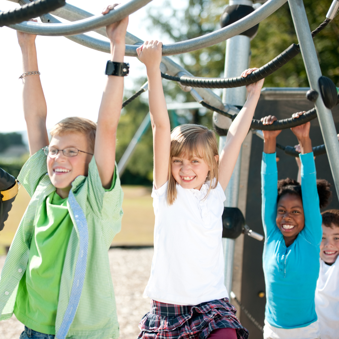 Smiling school age kids using in playground equipment