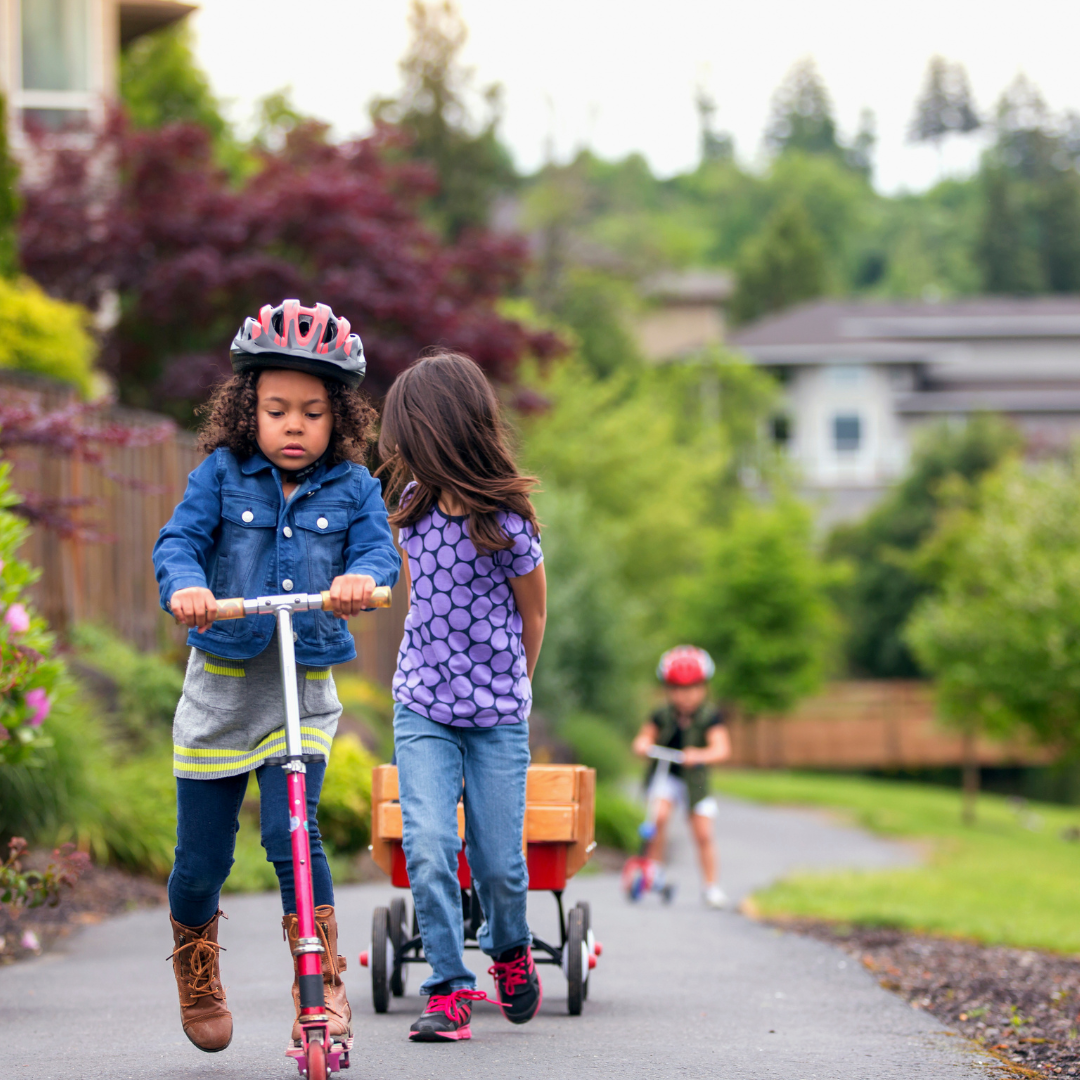 Children outside on scooters and pulling a wagon