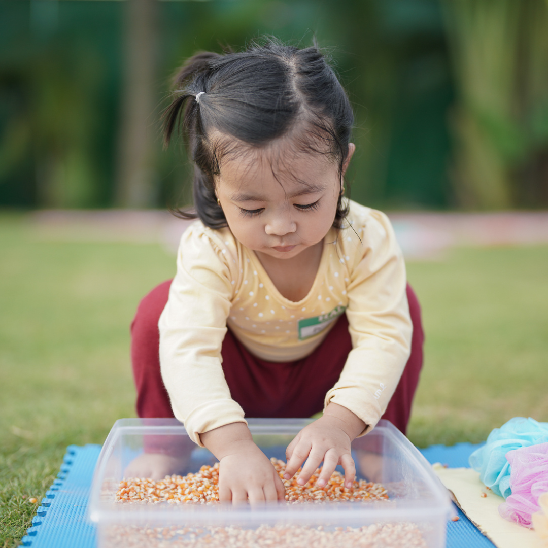 Toddler playing outside with sensory bin
