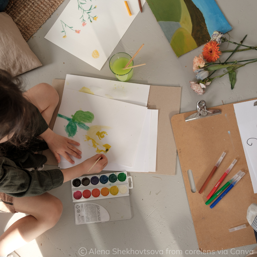 Child sitting inside on the ground, painting