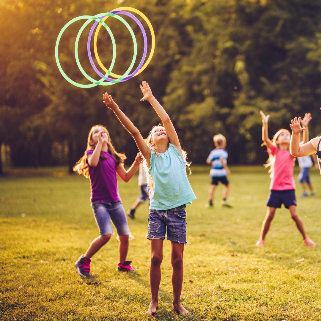 Children playing with hula hoops outside on the grass