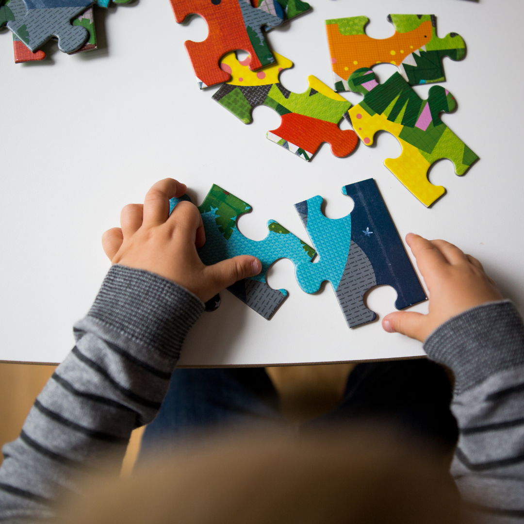 Child's hands doing a puzzle with large pieces