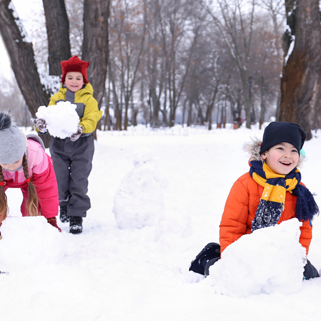 Children rolling snowballs outside