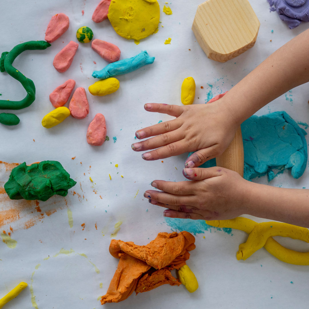 A child's hands creating with colourful playdough