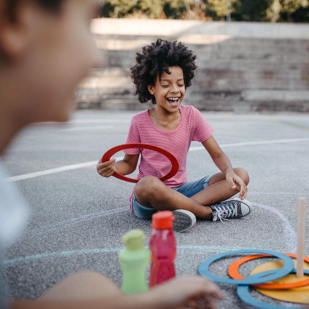Smiling children sitting outside, doing activity - Before and After School at Rick Hansen PS