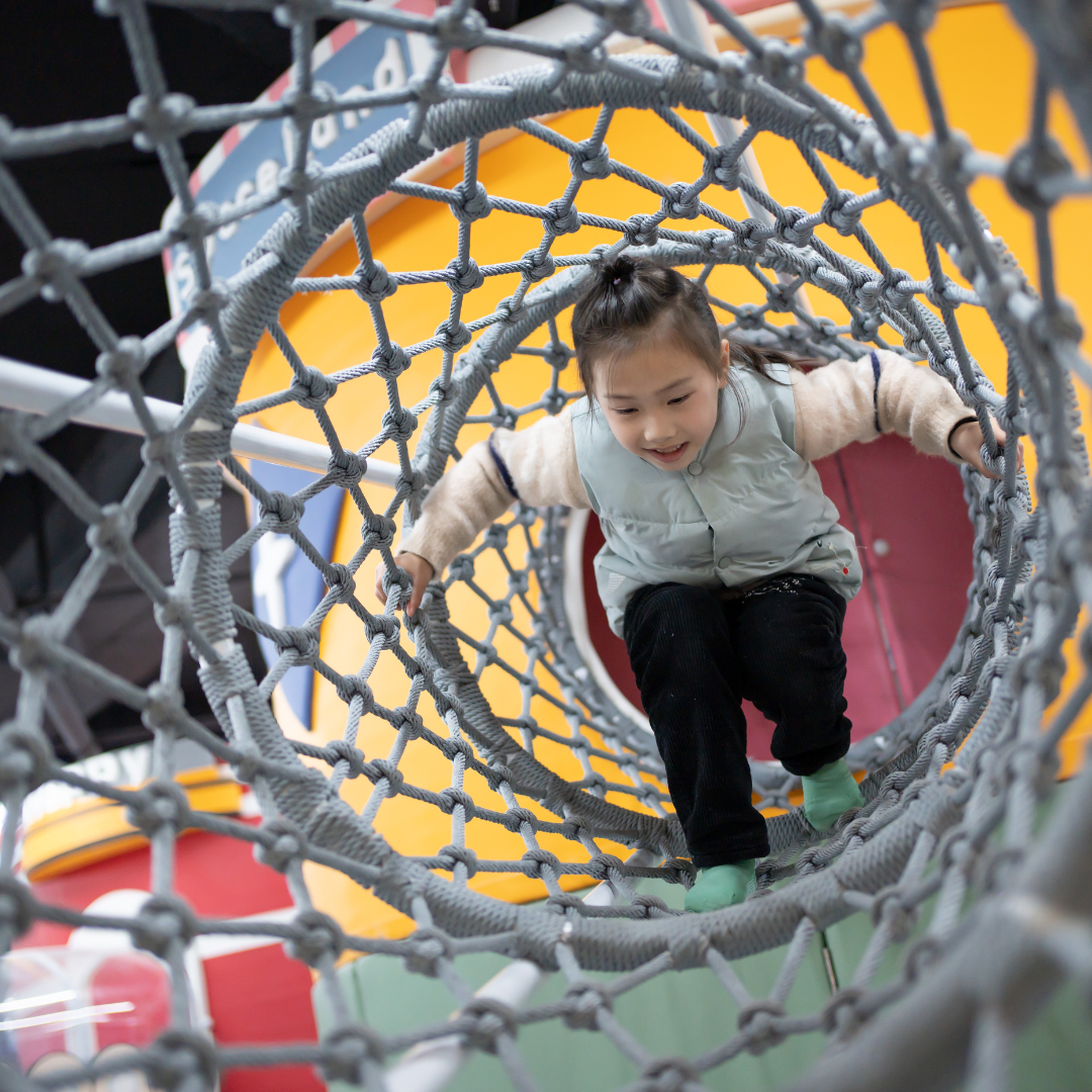 Child climbing through playground net structure - Before and After School at Teston Village PS