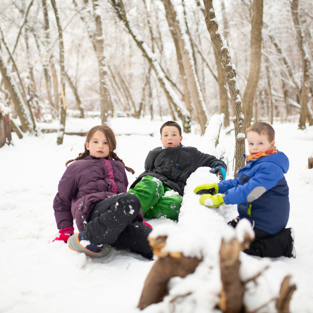 Children sitting in and playing with snow