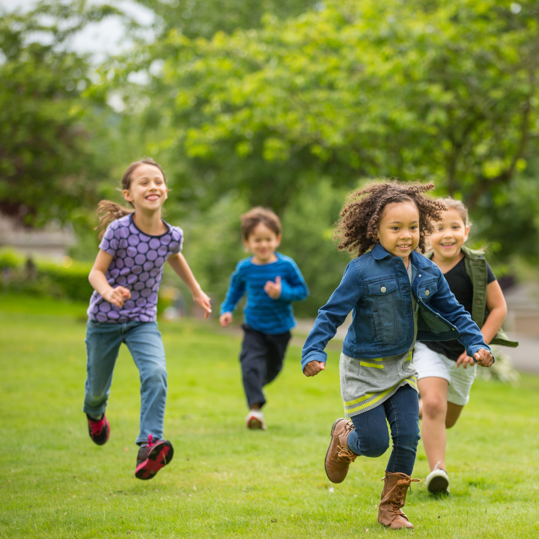 School age children running outside on grass