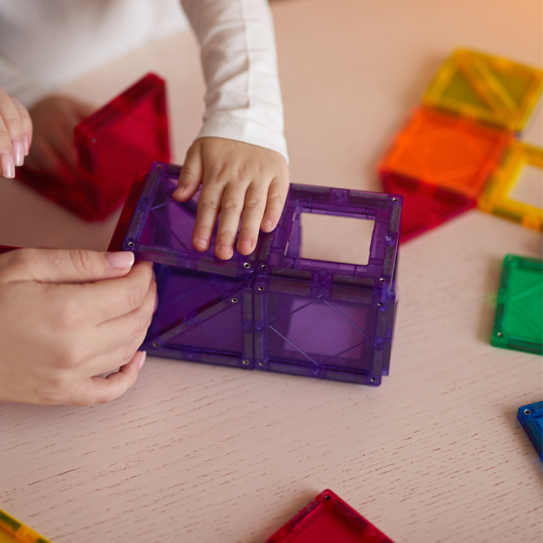 Child and adults hands, building with magnet tiles