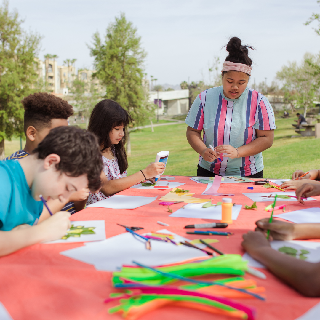 School age children doing crafts outside at table