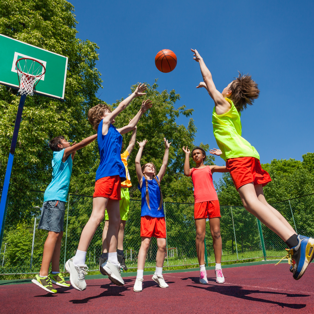 Kids jumping while playing basketball outside