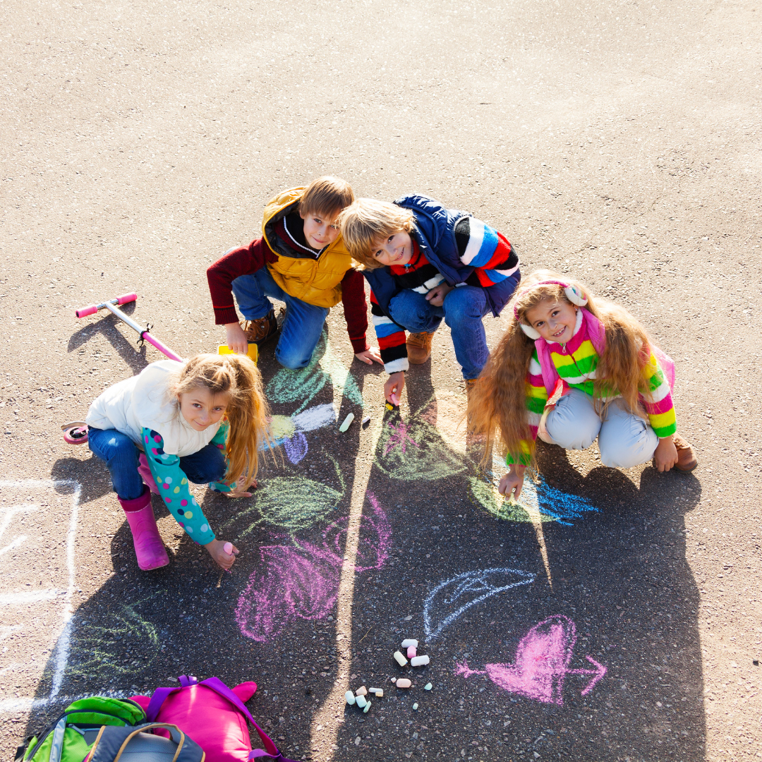 School age kids outside doing chalk on the ground