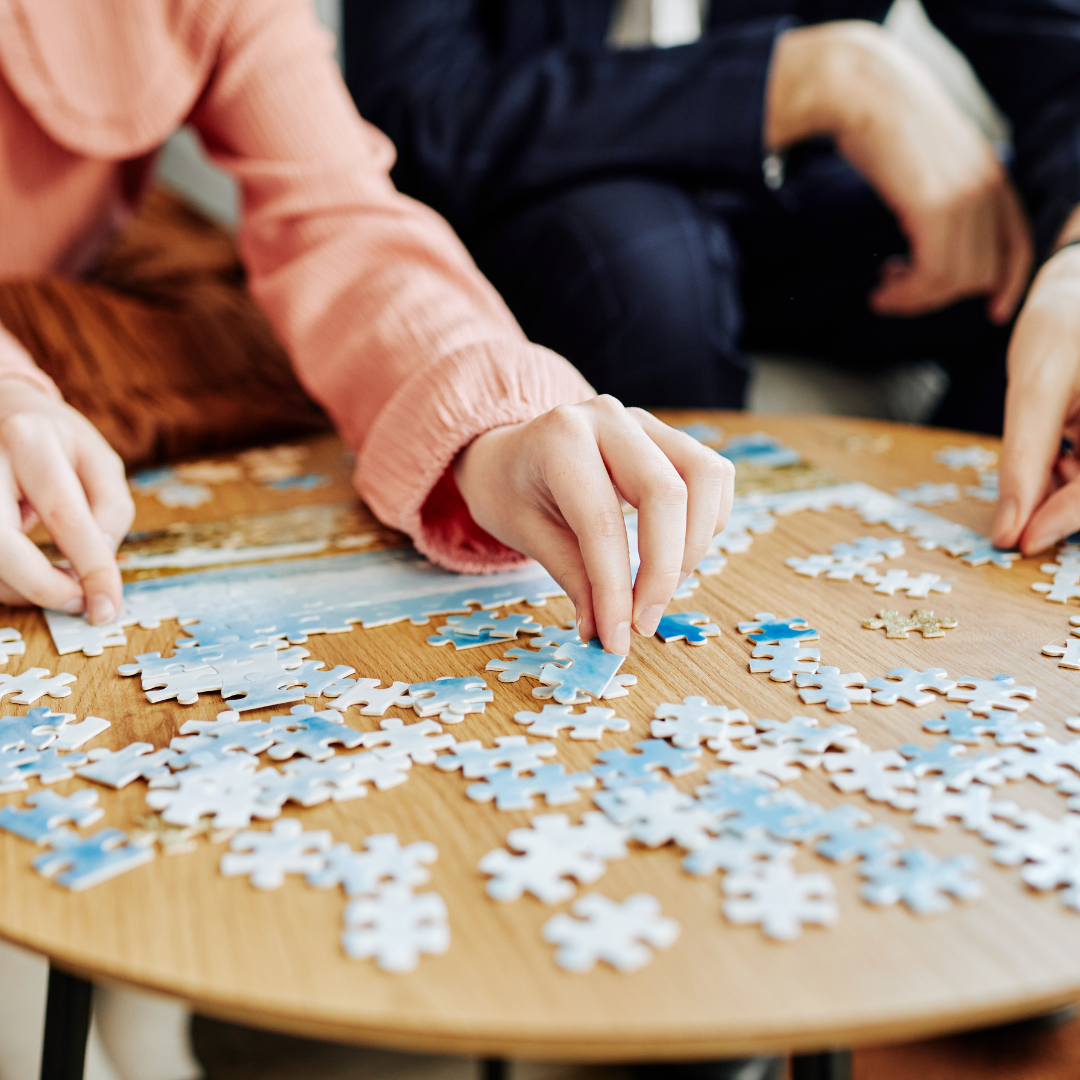 Hands of two people doing puzzles