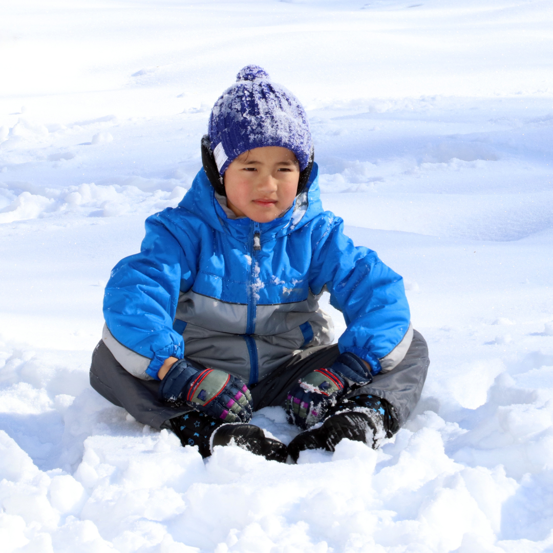 Child sitting in the snow - Before and After School at Canadian Martyrs CES