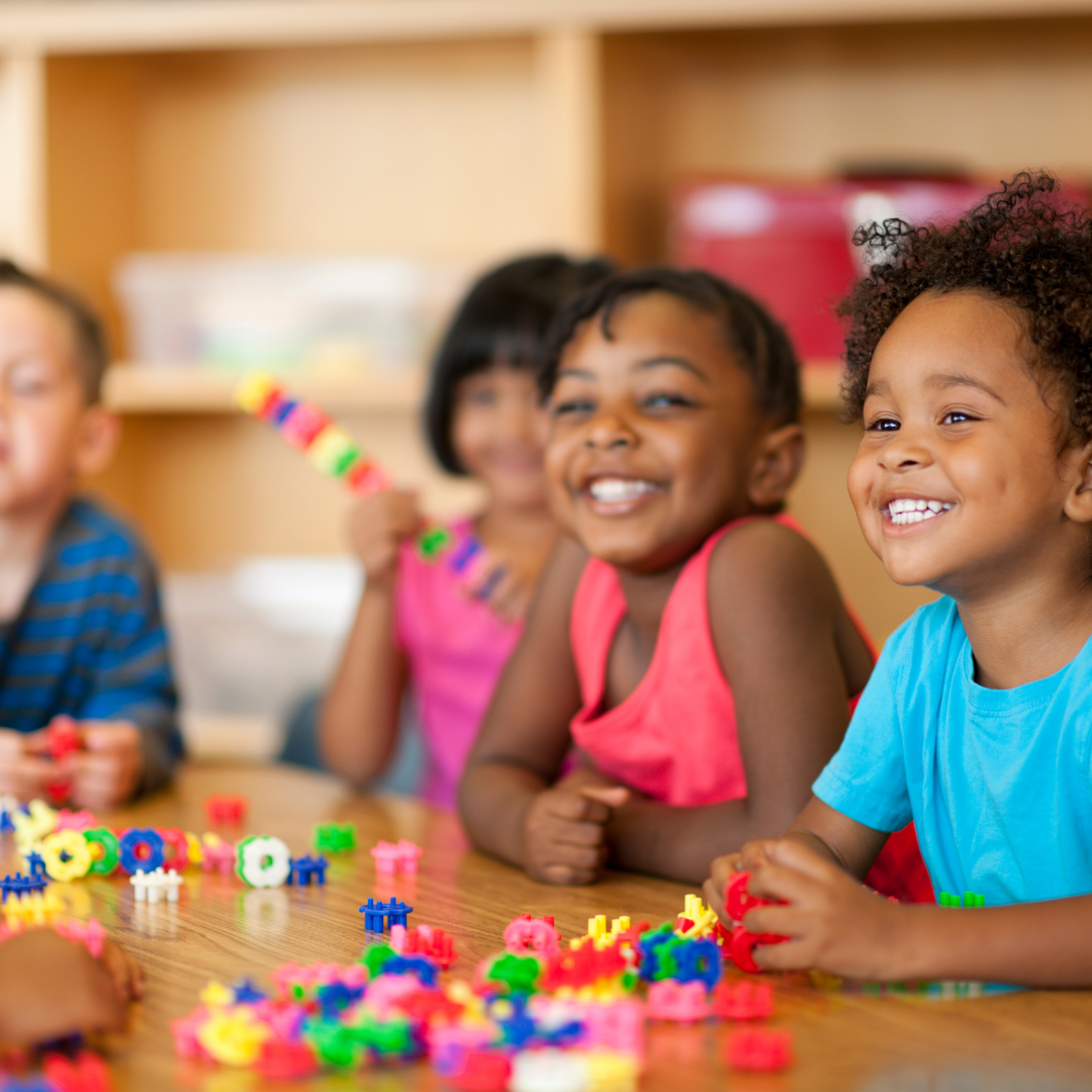 Smiling children playing activities at a classroom table