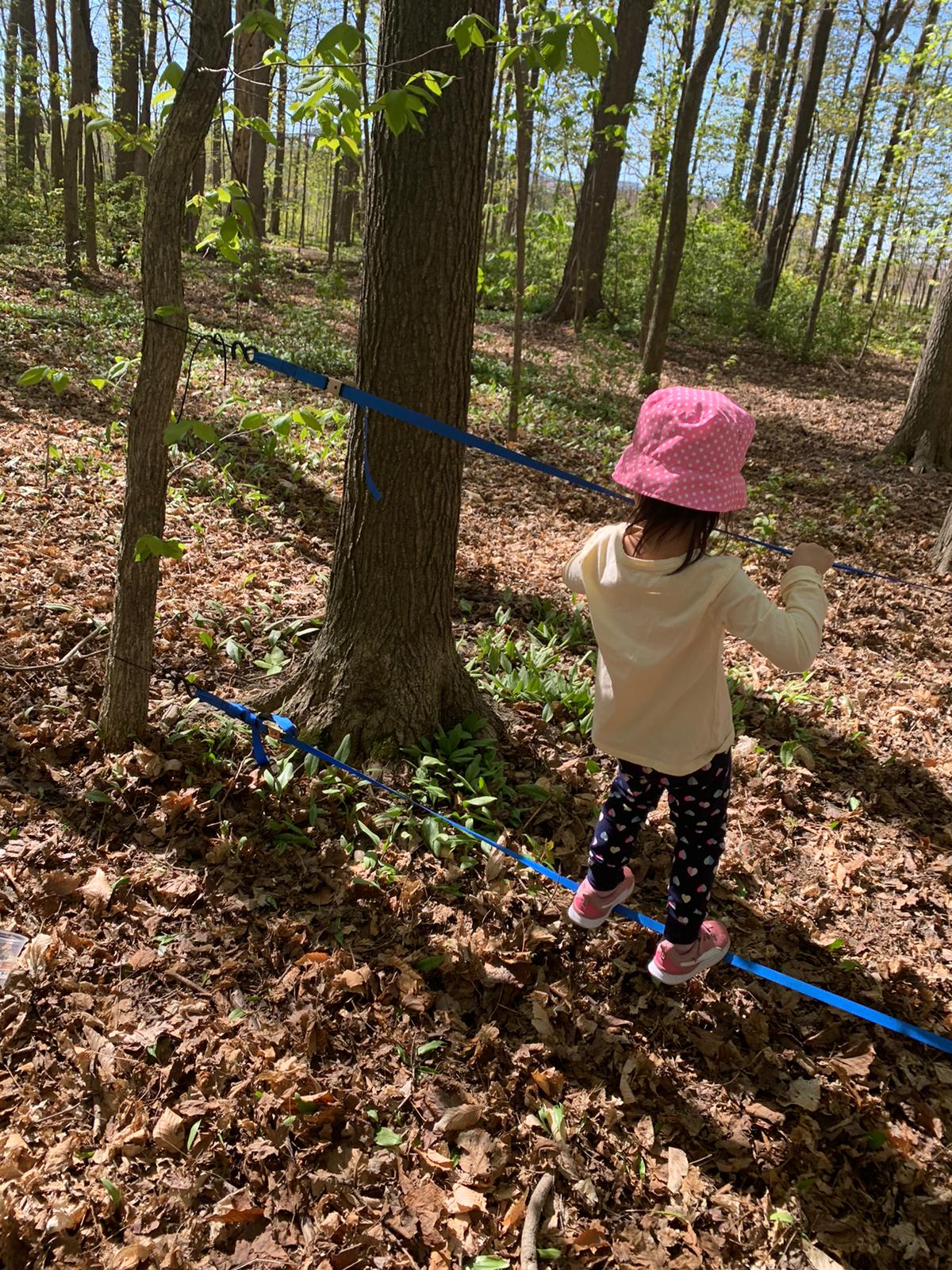 Child balancing on low slack line outside in nature