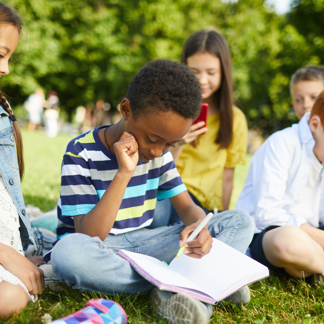 School age kids sitting and working outside