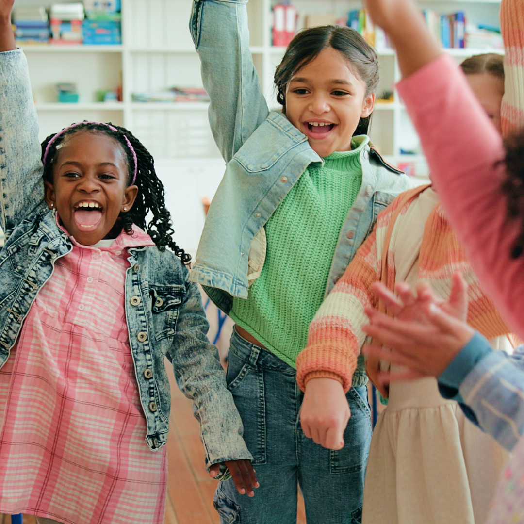 Happy school age kids raising their arms in the air
