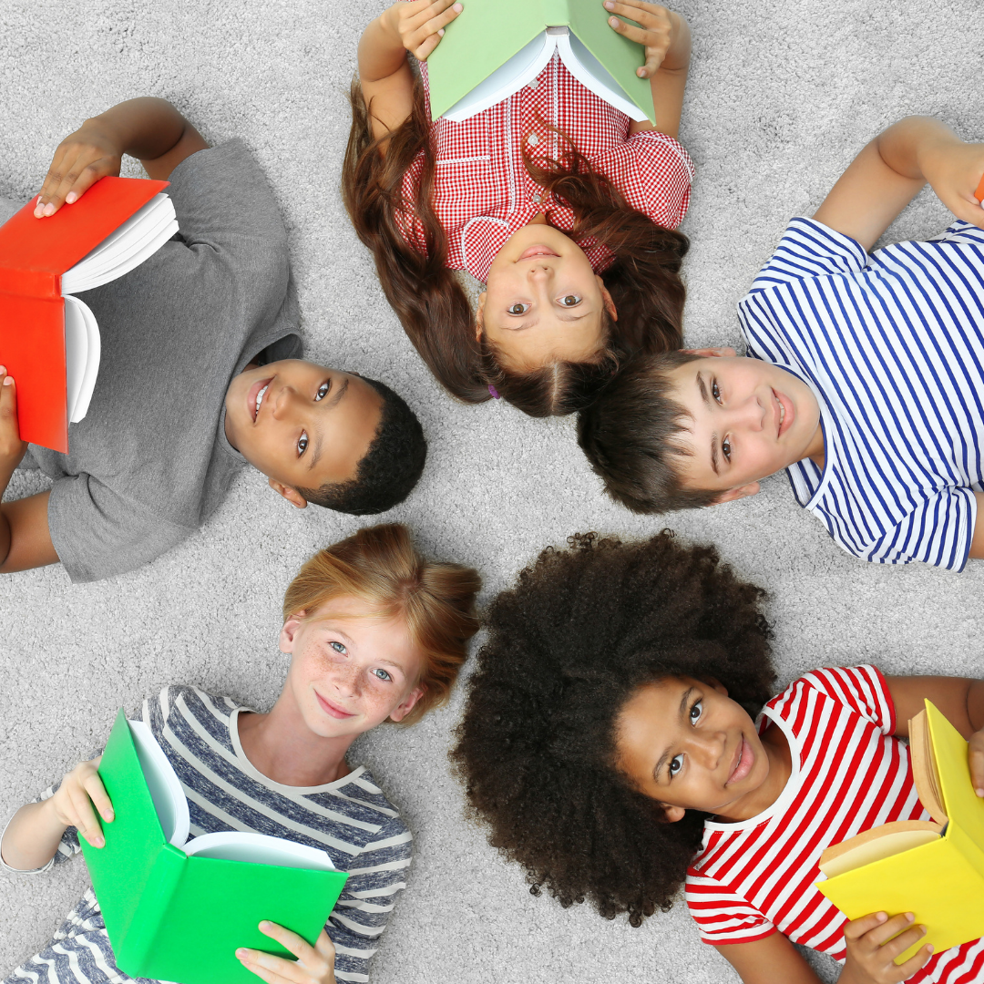 Birds eye view of five kids lying down, each holding a book in a circle