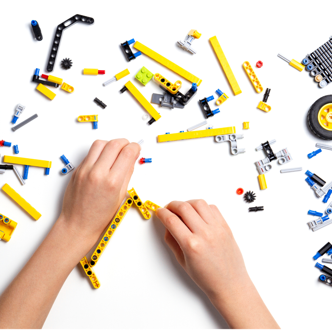 A child's hands constructing with loose plastic parts and wheels
