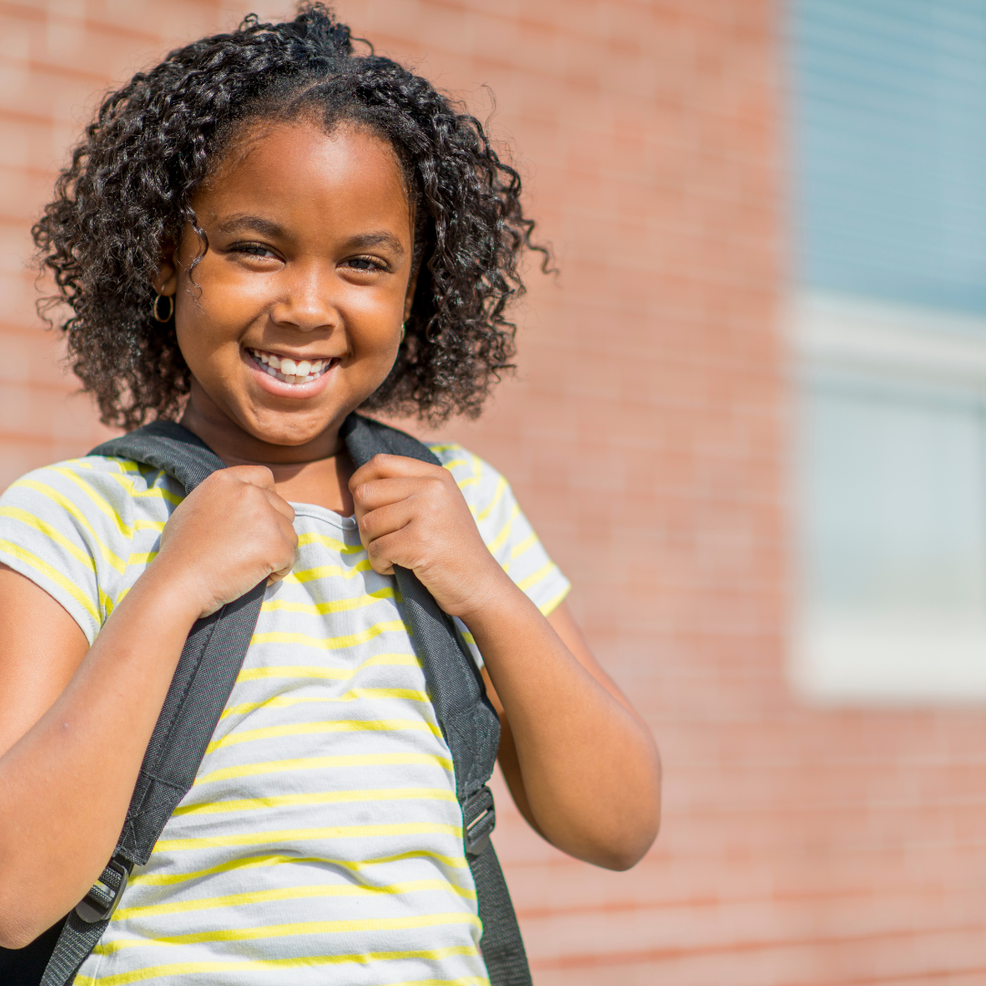 Smiling school age child standing outside of a building