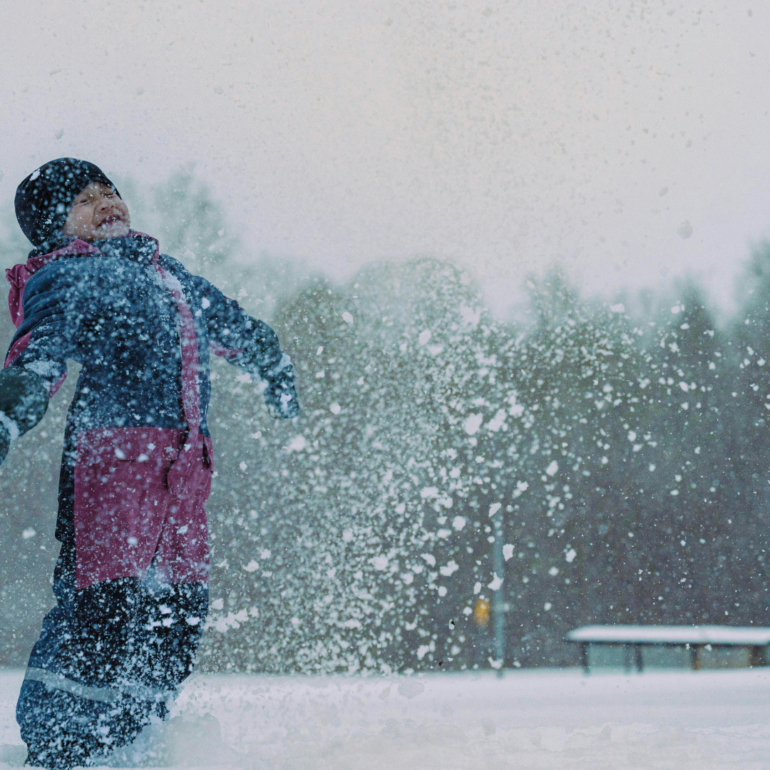Happy child standing and stretching out their arms in snow