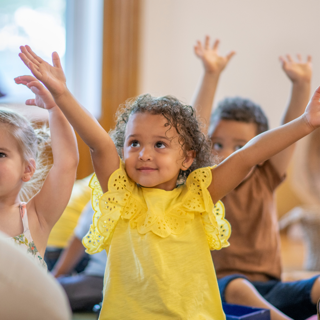 Group of young children raising arms up inside