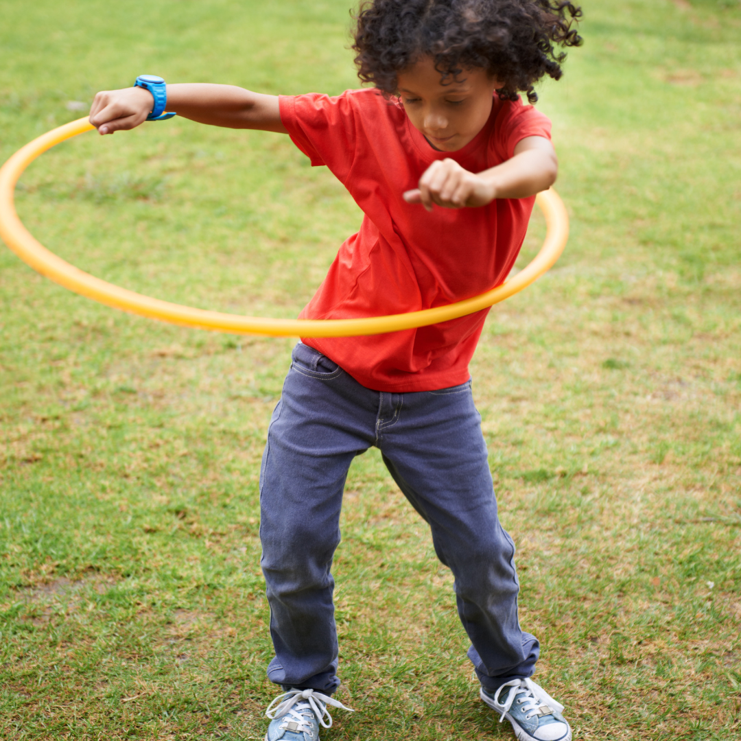 School age child hula hooping outside on grass
