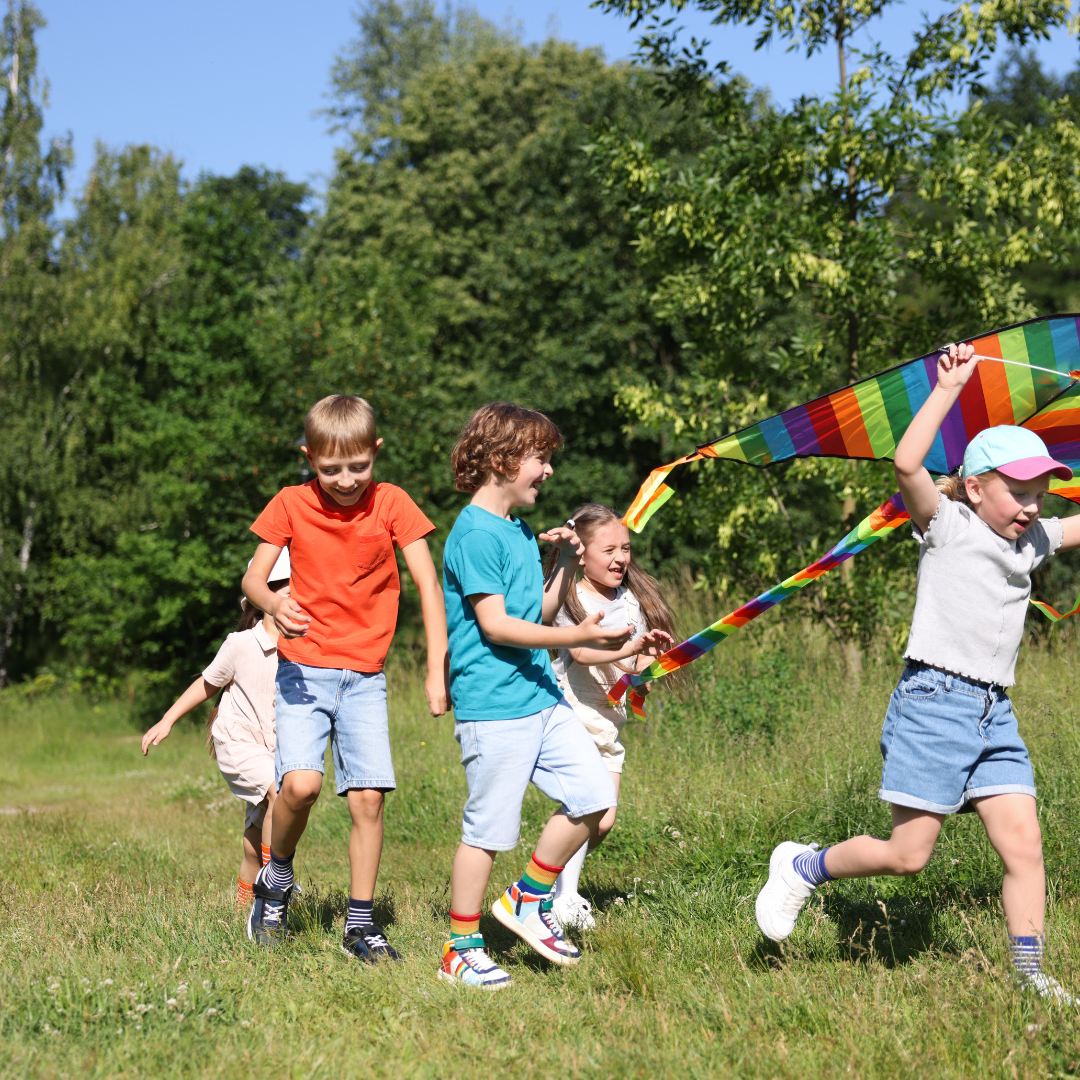 School age children running with colourful kite