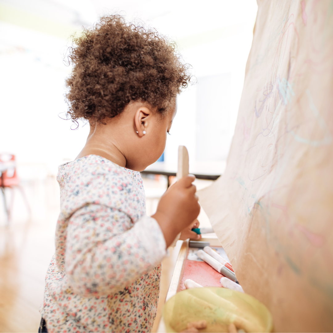 Toddler standing at easel doing art