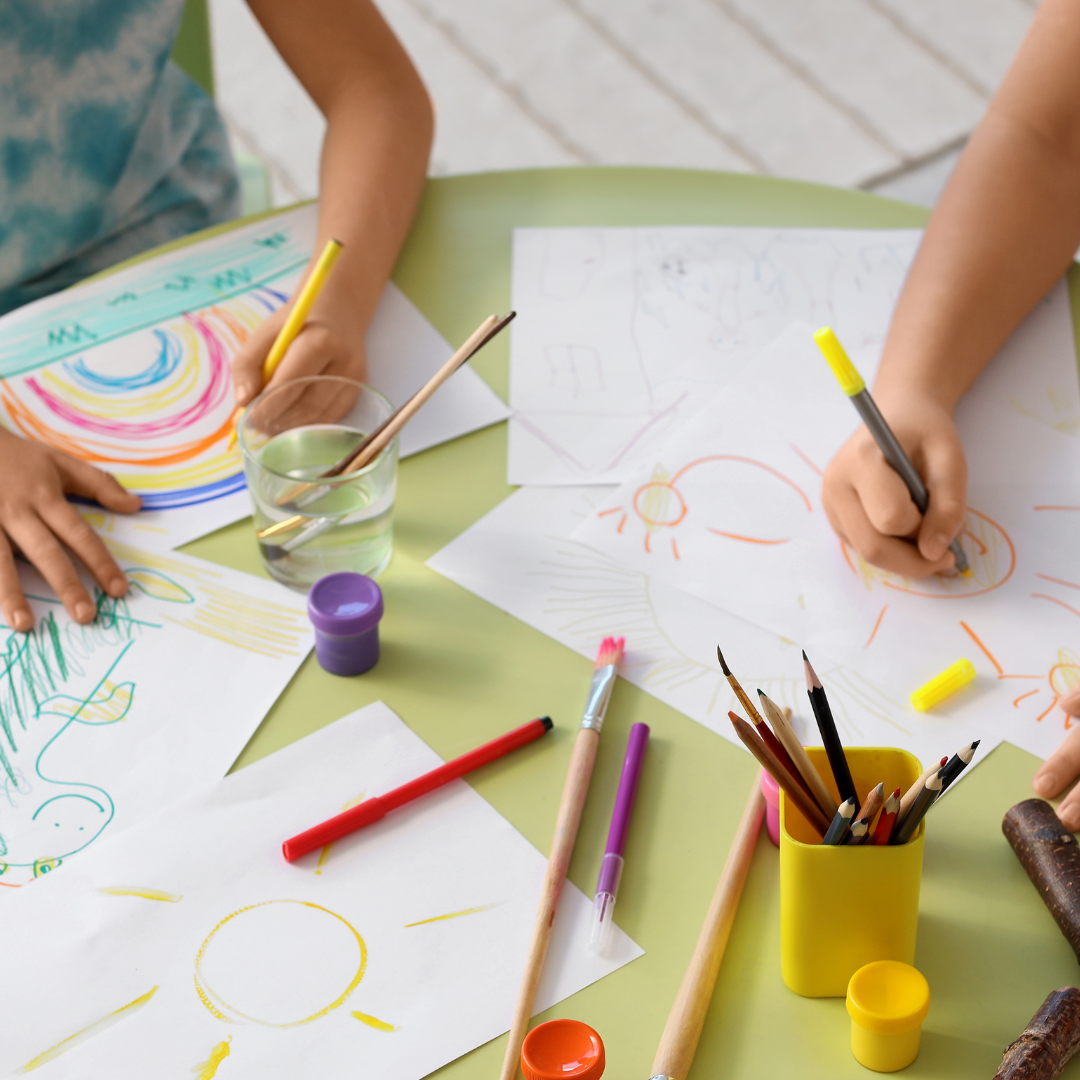 Kids at a table, drawing using pencil crayons
