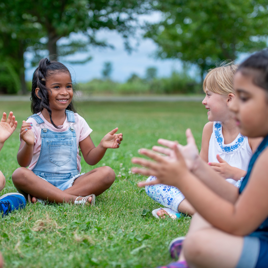 Kindergarten children sitting outside on the grass