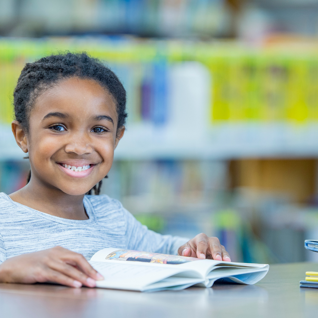 Smiling school age child reading at a table