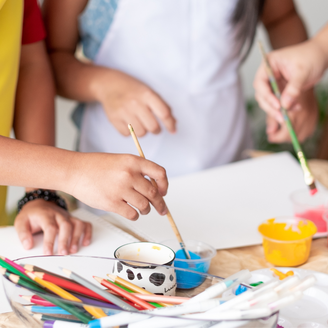 Children's hands painting with small brushes