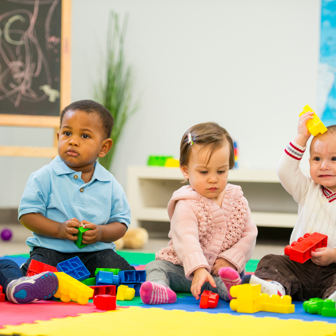 Toddlers playing with blocks on floor mat