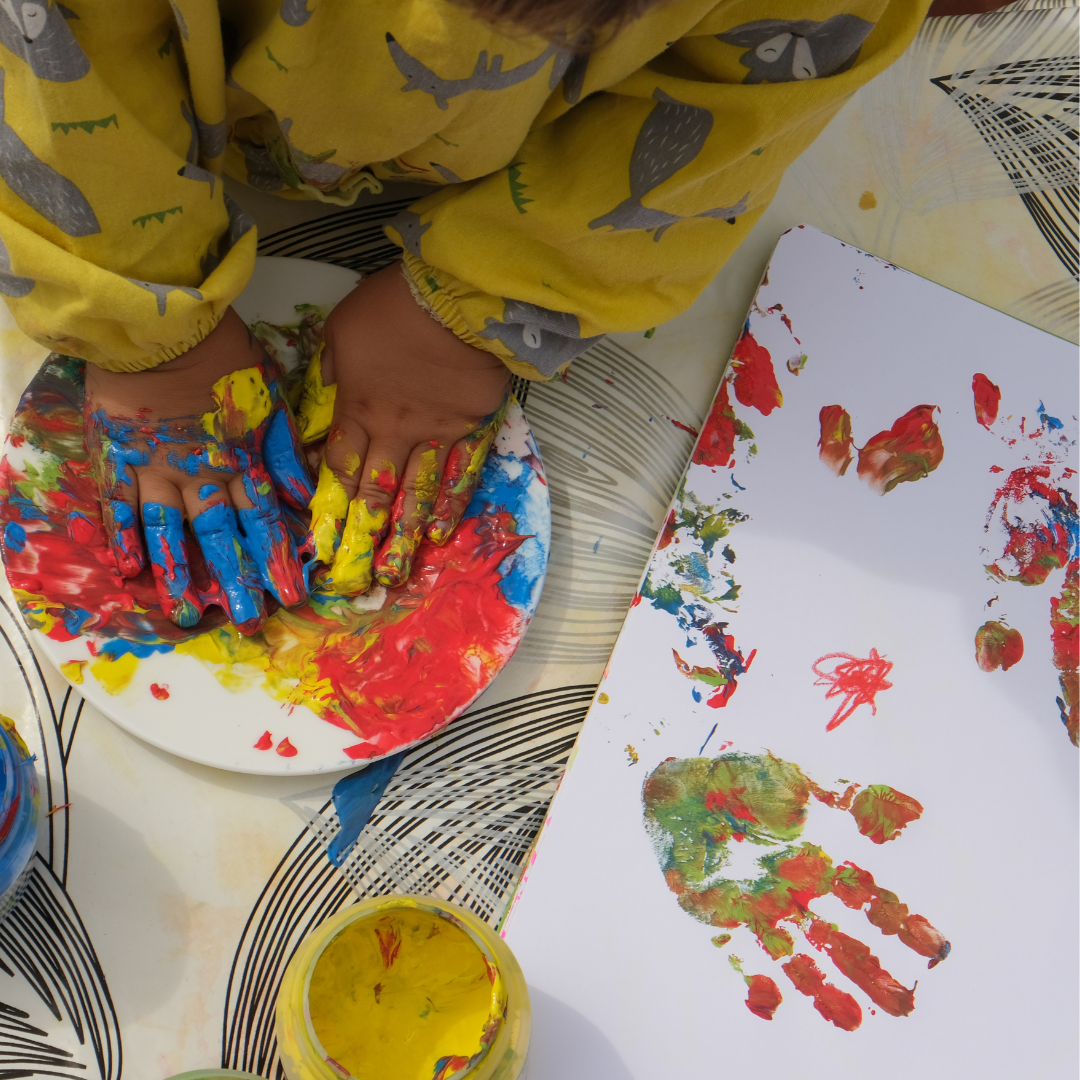 Child doing a painted handprint activity