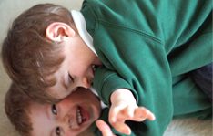 Two children lying down hugging and smiling