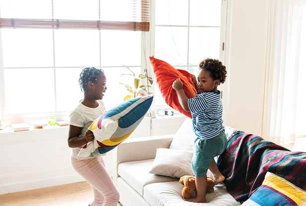 Two children pillow fighting and smiling