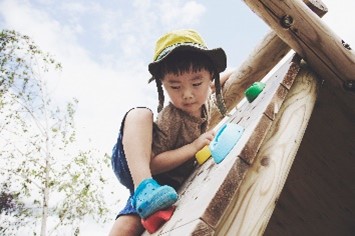 A child climbing outside on a playground structure