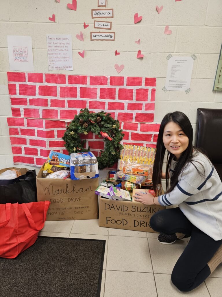 One adult crouched down to show the childcare centre's food donation boxes at Upper Canada Child Care head office