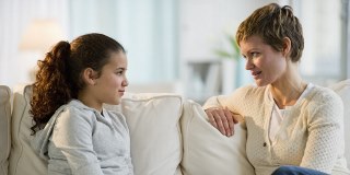 School age child sitting on couch facing an adult - appear to be in conversation