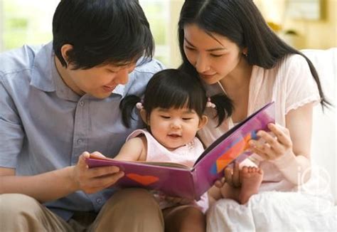 Adult, toddler, and adult sitting and reading a book together.