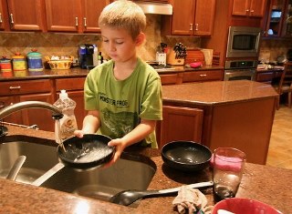 School age child washing dishes in a kitchen