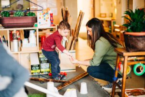 Preschooler and educator working together on a project in a classroom