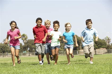 Group of smiling school age children running in a school yard field