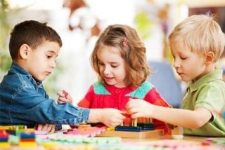 Three children playing games at a table inside