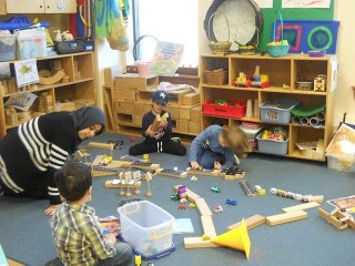 An educator playing blocks on the floor with children